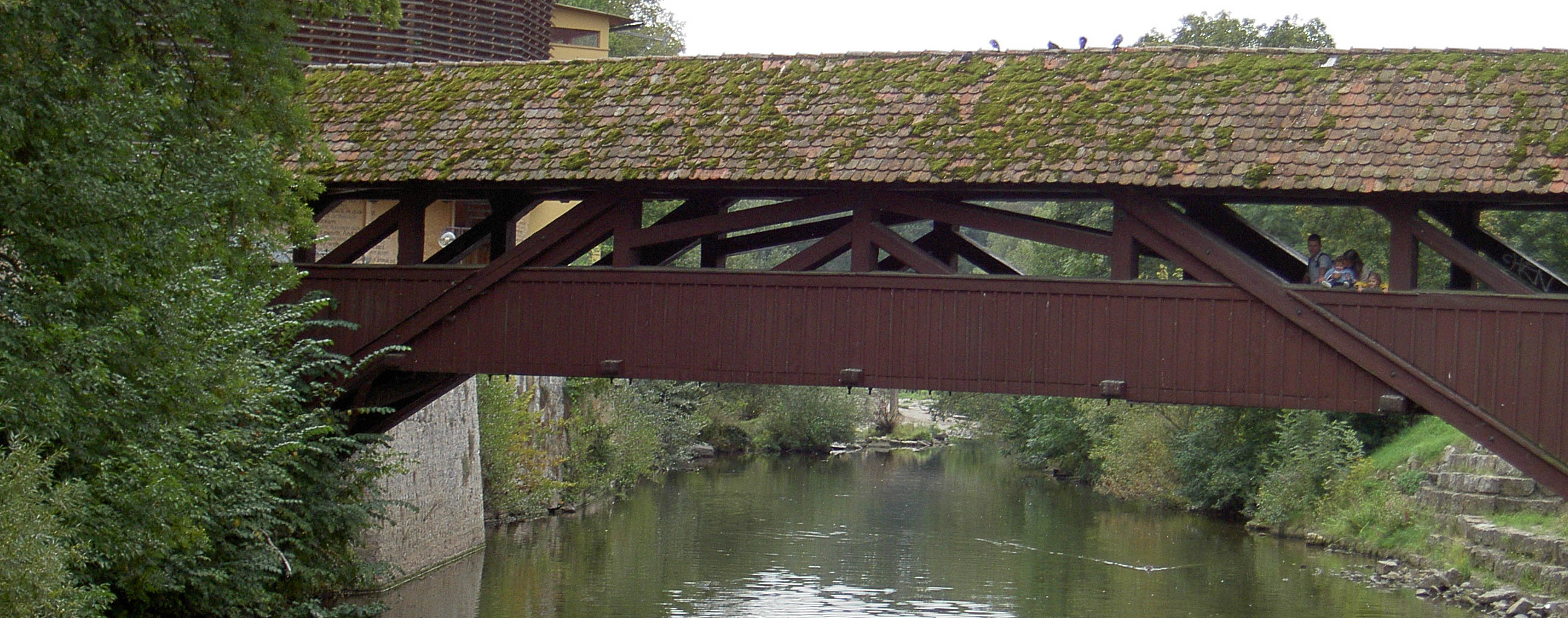 überdachte Brücke über einen Fluss