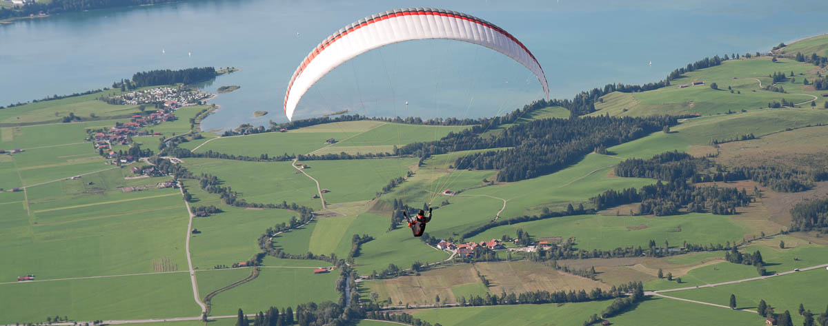 Gleitschirmflieger in der Luft über einem See