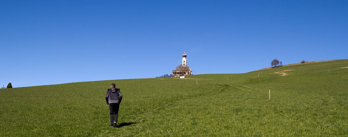 einsamer Wanderer auf dem Weg zu einer Kirche in den Bergen