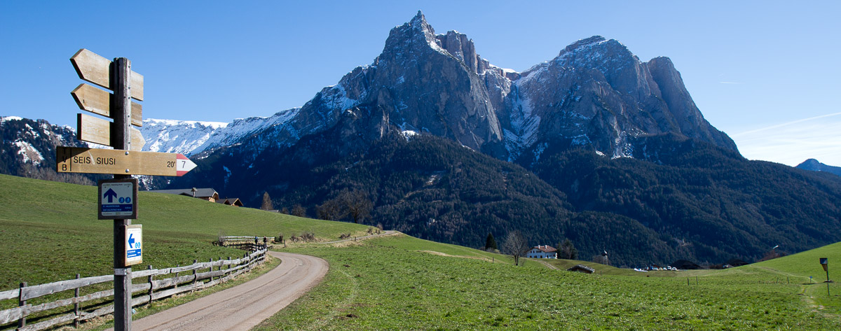 Wegweise mit Bergmassiv im Hintergrund in Südtirol