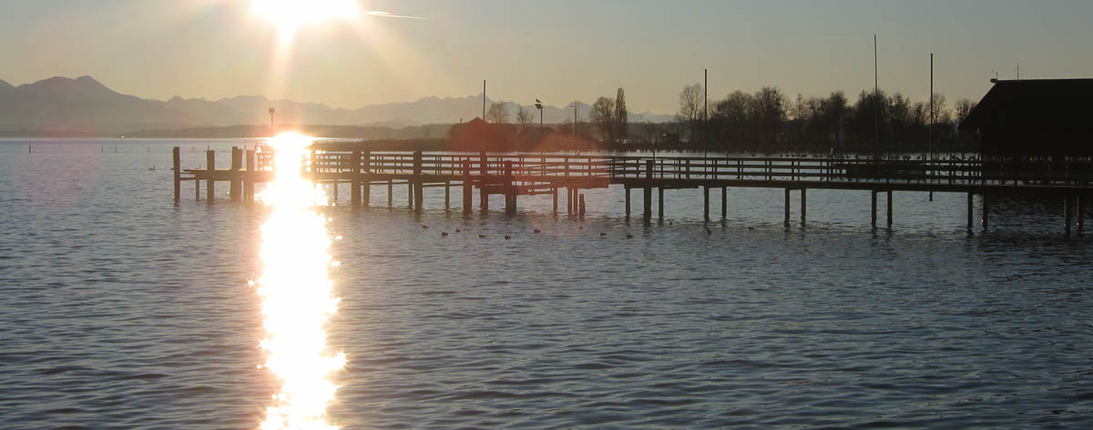 Steg mit glitzerndem Sonnenstrahl am Chiemsee